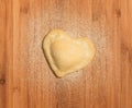 Fresh,handmade,single raviolo in the shape of heart,covered with flour and placed on the wooden table and covered with flour. Royalty Free Stock Photo