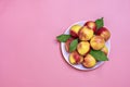 Fresh harvested nectarines, plate, leaves lies round on pink background Vegetables vitamin Keratin Natural Peach Organic