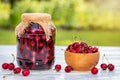 Fresh harvested red cherries and preserved fruit in jar