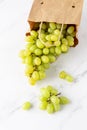 Fresh harvesting seedless green yellow grape bunch falling from paper bag