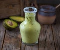 Fresh healthy Avocado honey shake with raw fruit served in jar isolated on wooden table side view