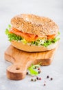 Fresh healthy bagel sandwich with salmon, ricotta and lettuce on vintage chopping board on white kitchen table background. Healthy Royalty Free Stock Photo