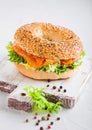 Fresh healthy bagel sandwich with salmon, ricotta and lettuce on vintage chopping board on white kitchen table background. Healthy Royalty Free Stock Photo
