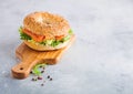 Fresh healthy bagel sandwich with salmon, ricotta and lettuce on vintage chopping board on white kitchen table background. Healthy Royalty Free Stock Photo