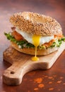 Fresh healthy bagel sandwich with salmon, ricotta and soft egg on vintage chopping board on rustic kitchen table background. Healt Royalty Free Stock Photo