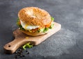 Fresh healthy bagel sandwich with salmon, ricotta and soft egg on vintage chopping board on stone kitchen table background. Health Royalty Free Stock Photo