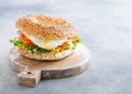 Fresh healthy bagel sandwich with salmon, ricotta and soft egg on vintage chopping board on white kitchen table background. Royalty Free Stock Photo