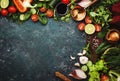 Fresh healthy food cooking or salad making ingredients on dark background with rustic wooden board. Diet or vegetarian food Royalty Free Stock Photo