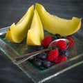 Fresh healthy fruit on a glass dessert plate on black background. Healthy eating concept Royalty Free Stock Photo