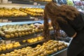 Fresh healthy fruits on shelves in supermarket. With a woman choosing best fruits