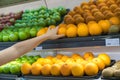 Fresh healthy fruits on shelves in supermarket. With a woman hand choosing best fruits