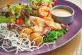 Fresh and healthy grilled seafood salad octopus, squid and shrimp, tomatoes and rice chips in a purple plate on a wooden