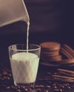 Fresh healthy milk pouring from the jug into a glass and chocolate coffee cookies Royalty Free Stock Photo