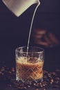 Fresh healthy milk pouring from the jug into a glass off cold latte and chocolate coffee cookies Royalty Free Stock Photo