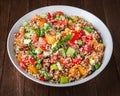 Fresh healthy salad with quinoa, colorful tomatoes, sweet pepper, cucumber and parsley on wooden background close up. Royalty Free Stock Photo