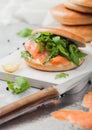 Fresh healthy sandwich with salmon and bagel, cream cheese and wild rocket with knife on white background Royalty Free Stock Photo