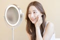 Fresh healthy skin, beautiful smile of asian young woman, girl looking at mirror, applying moisturizer on her face, putting cream Royalty Free Stock Photo