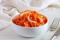 Fresh healthy vegetarian carrot salad with apple, onion and spices in the bowl with fork and knife. Side view, close up Royalty Free Stock Photo