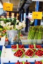Fresh heap of garlic  in a bucket, strawberries and asparagus displayed on the grocery market stall Royalty Free Stock Photo