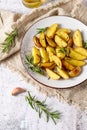 Fresh homemade baked potatoes with olive oil, rosemary and garlic on vintage plate over linen towel Royalty Free Stock Photo