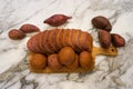 Fresh homemade baked purple japanese sweet potato bread in sliced loaf and buns on wooden cutting board on white marble table top Royalty Free Stock Photo