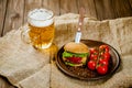 Fresh homemade beef burger on rustic wooden serving table with glass of beer. Selective focus. Royalty Free Stock Photo