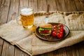 Fresh homemade beef burger on rustic wooden serving table with pint of beer. Selective focus. Royalty Free Stock Photo