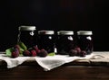 Fresh homemade blackberry jam in glass jar on a wooden background. Several fresh berries are near it. Created with