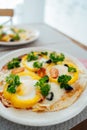 Fresh homemade breakfast pizza on bread wrap with eggs, cheese, tomatoes, bell pepper and herbs on the served table Royalty Free Stock Photo