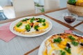 Fresh homemade breakfast pizza on bread wrap with eggs, cheese, tomatoes, bell pepper and herbs on the served table Royalty Free Stock Photo