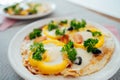 Fresh homemade breakfast pizza on bread wrap with eggs, cheese, tomatoes, bell pepper and herbs on the served table Royalty Free Stock Photo