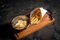 Fresh homemade burger on little cutting board with grilled potatoes, served with ketchup sauce and sea salt over wooden table with