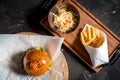 Fresh homemade burger on little cutting board with grilled potatoes, served with ketchup sauce and sea salt over wooden table with