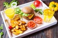 Fresh homemade burgers, fried potatoes, beer and juice served on white tray Royalty Free Stock Photo