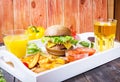 Fresh homemade burgers, fried potatoes, beer and juice served on white tray Royalty Free Stock Photo