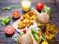 Fresh homemade burgers, fried potatoes, beer and juice served on wood table Royalty Free Stock Photo