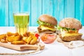 Fresh homemade burgers, fried potatoes and beer served on white wood table Royalty Free Stock Photo