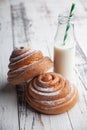 Fresh homemade cinnamon rolls on a wooden white desk and milk in glass bottle Royalty Free Stock Photo