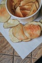 Fresh homemade deep fried crispy potato chips in white box on a wooden background, top view. Salty crisps scattered on a table for Royalty Free Stock Photo