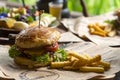 Fresh homemade delicious grilled burger with potato fries on old wooden table background board in a rustic, Side view, Close up,