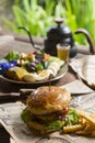 Fresh homemade delicious grilled burger with potato fries on old wooden table background board in a rustic, Side view, Close up,