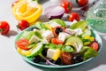 Fresh homemade greek salad with basil leaves on a plate and ingredients for cooking on the table. Domestic life. Hard light Royalty Free Stock Photo