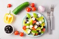 Fresh homemade greek salad with basil leaves on a plate and ingredients for cooking on the table. Domestic life. Top view Royalty Free Stock Photo