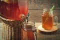 Fresh homemade Kombucha fermented tea drink in jar with faucet and in cans-mugs on wooden background