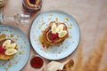 Fresh homemade pancakes with red currants and caramel on gray plate and craft background with black and strong coffee.