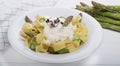 Fresh homemade pasta dish of fettuccine or tagliatelle, green asparagus, white sauce, white plate