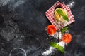 Fresh homemade pasta tagliatelle on wooden spoon with pasta ingredients tomatoes, raw egg, basil leaf on the dark concrete backgro Royalty Free Stock Photo