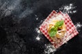 Fresh homemade pasta tagliatelle on wooden spoon with pasta ingredients tomatoes, raw egg, basil leaf on the dark concrete backgro Royalty Free Stock Photo
