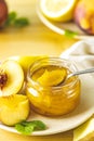 Fresh homemade peach jam in glass jar on a wooden background. Several fresh berries, lemon and mint are near it