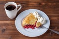 Fresh homemade pie with cherry pulp and ice cream on a plate. A slice of a cherry pie with a ruddy crust on a wooden table. Cherry